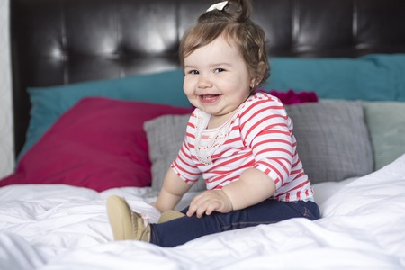 A one year old girl in bed having fun
