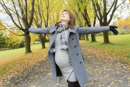 A Beautiful pregnant woman in the autumn parkの写真素材