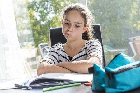 A schoolgirl studying with books on the kitchen table