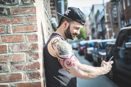 A sexy man with tattoo outside in a city streetの写真素材