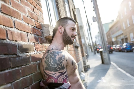 A sexy man with tattoo outside in a city streetの写真素材