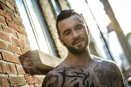 A sexy man with tattoo outside in a city streetの写真素材