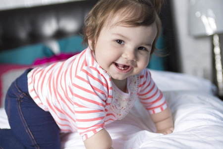 A one year old girl in bed having funの写真素材