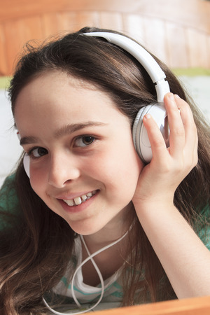 A children girl listening music lay on his bedの写真素材