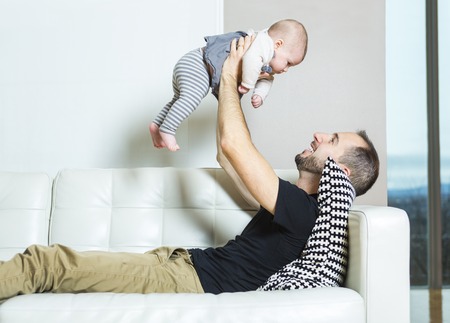 A father with baby on the sofa taking good timeの写真素材