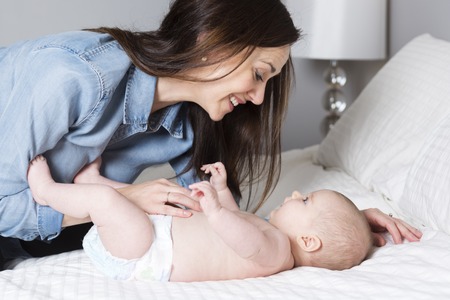 A mother with baby on bed having fun