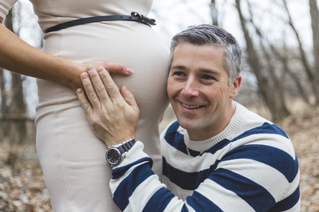 A beautiful outdoor pregnant couple portrait in autumn natureの写真素材