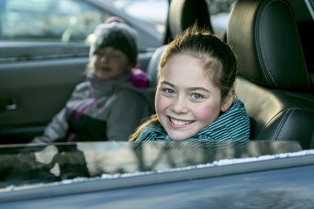 A caucasian girl in warm clothes traveling in a car seat