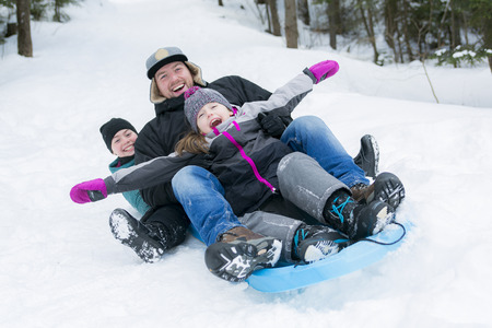 A Father and daughters sledding at winter time