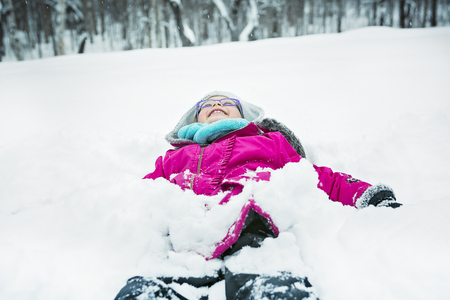 A Little Girl Playing with Snow Outdoors in Winterの写真素材