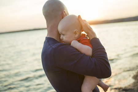 A happy joyful father with baby on sunsetの写真素材