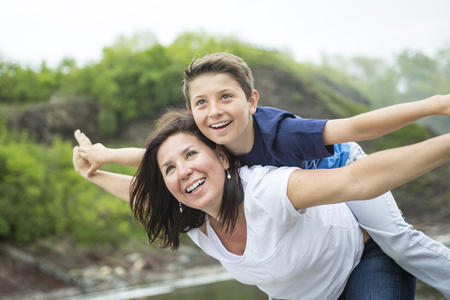 A mother and son playing in front of a waterfallの写真素材