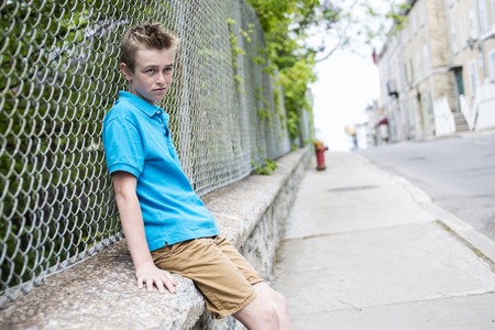 A young teen boy looking out of a fenceの写真素材