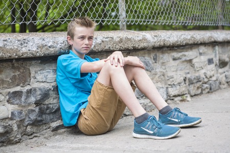 A boy standing in the city street look awayの写真素材