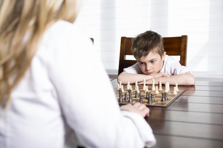 A boy playing chess at home with motherの写真素材