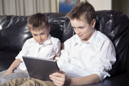 Two Children playing with tablet pc in the living roomの写真素材