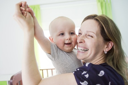 A Happy mother with her baby boy at home in bedroomの写真素材