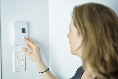A Woman Adjusting On Home Heating Systemの写真素材