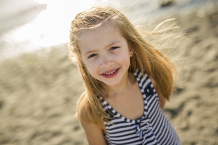 A Cute little girl standing close to beach at sunset