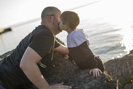 A Son on father shoulders at the beach having fun at sunset togetherの写真素材