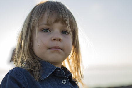 A Cute little girl standing close to beach at sunsetの写真素材