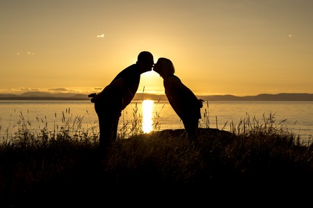 A Silhouettes of romantic couple on tropical beach at sunsetの写真素材