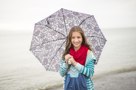 A Girl enjoying the rain and having fun outside on the beach on a gray rainy