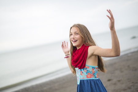A Girl enjoying the rain and having fun outside on the beach on a gray rainyの写真素材