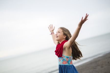 A Girl enjoying the rain and having fun outside on the beach on a gray rainyの写真素材