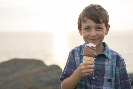 A boy eating a delicious ice cream on the sunset.の写真素材