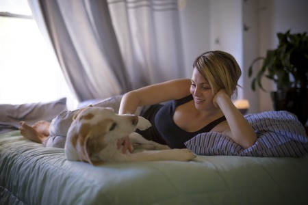 woman with her dog in the bed at homeの写真素材