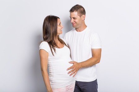 A caucasian couple expecting baby smiling cheerful on white