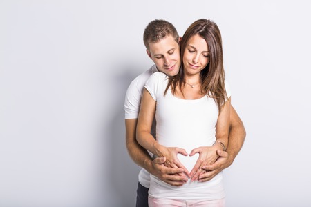 A caucasian couple expecting baby smiling cheerful on whiteの写真素材