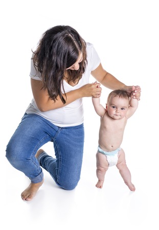 A baby taking first steps with mother help on white backgroundの写真素材