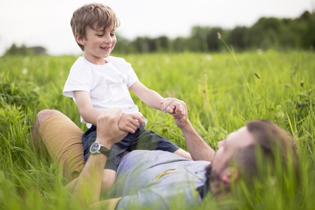 Father and son having fun outdoors in the meadowの写真素材