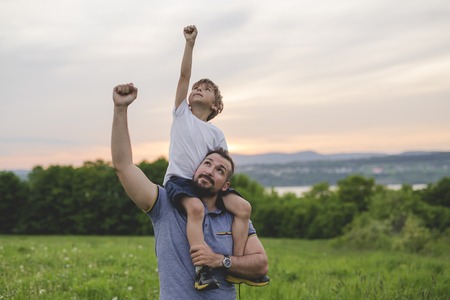 A Father and son having fun outdoors in the meadowの写真素材