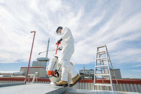A professional in protective uniform, mask, gloves in the roof for cleaningの写真素材