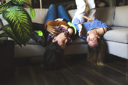 Two womans sitting on the couch take some good time at homeの写真素材