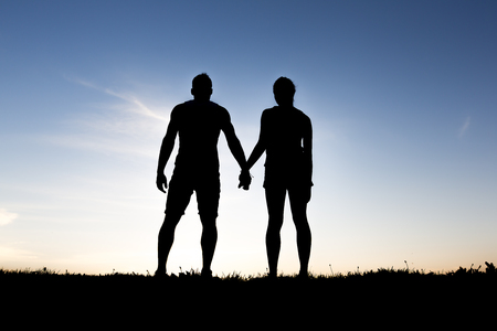 silhouette of romantic lovers with sunset on the backの写真素材