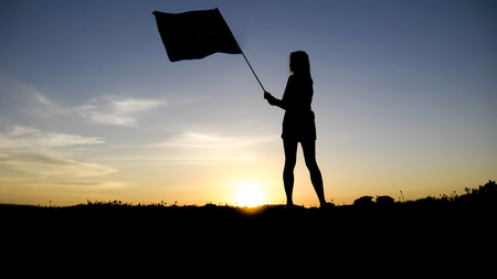 silhouette of people with flag on mountain top .の写真素材