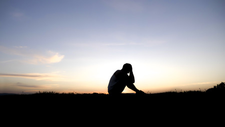 Sad young man silhouette worried at sunset