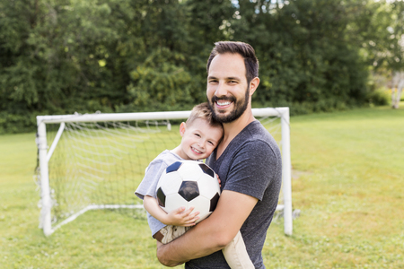 Young father with his little son playing football on football pitchの写真素材
