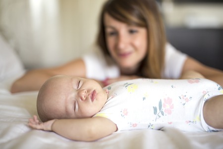 Portrait of mother with her 3 month old baby in bedroomの写真素材