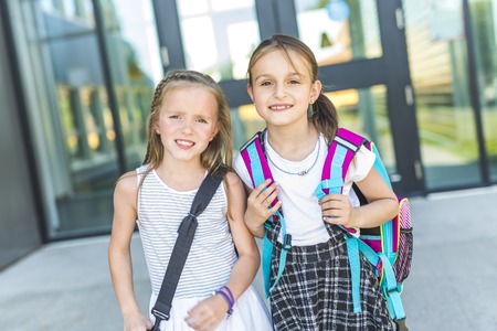 Two girls Standing Outside School With Book Bagsの写真素材
