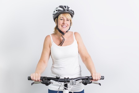 senior woman on the side of a bike in studio white backgroundの写真素材