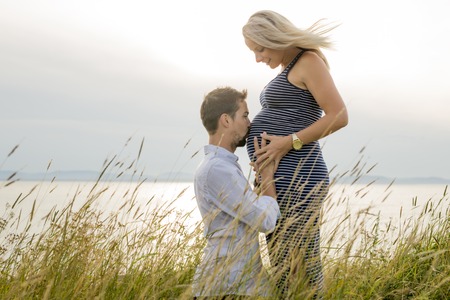 pregnant woman at beach with husband having funの写真素材