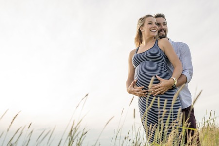 pregnant woman at beach with husband having funの写真素材