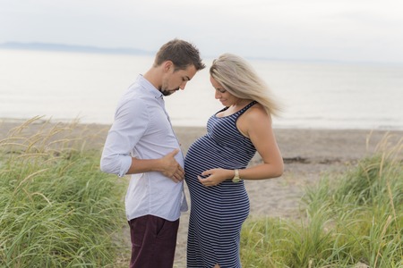 pregnant woman at beach with husband having funの写真素材