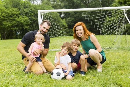 Happy family with football ball on a fieldの写真素材