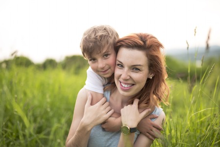 Cute kid boy with his mother on a summer meadowの写真素材